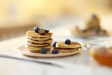 Photo of Tasty breakfast. Fresh pancakes with blueberries on white table, selective focus
