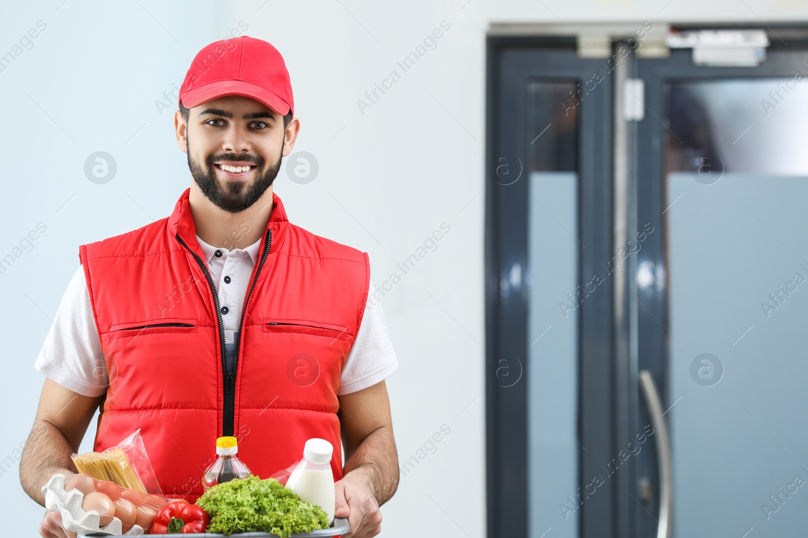 Photo of Man holding basket with fresh products indoors, space for text. Food delivery service