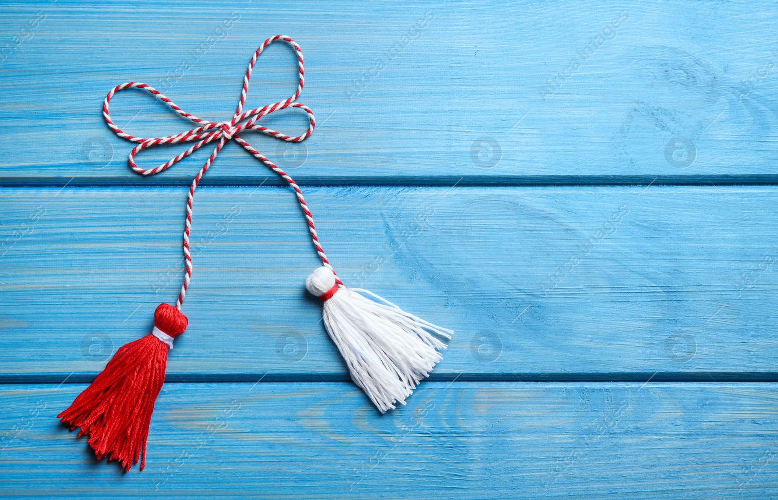 Photo of Traditional martisor on blue wooden background, top view with space for text. Beginning of spring celebration