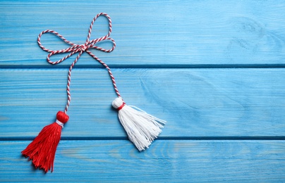 Photo of Traditional martisor on blue wooden background, top view with space for text. Beginning of spring celebration
