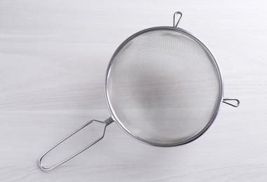 Photo of One metal sieve on white wooden table, top view