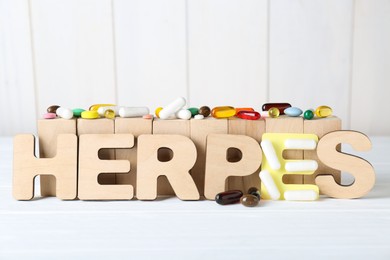 Word Herpes and different pills on white wooden table