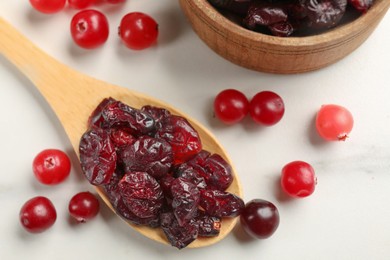Photo of Tasty dried cranberries and fresh ones on white table, top view