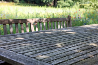 Empty wooden table with bench on sunny day in garden