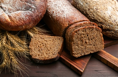 Different kinds of fresh bread on wooden table