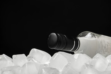 Photo of Bottle of vodka and ice cubes against black background. Space for text