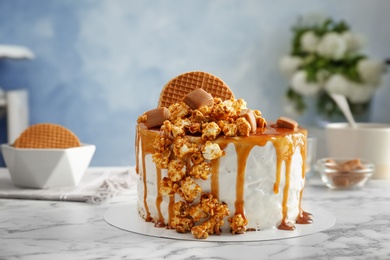 Delicious homemade cake with caramel sauce and popcorn on table