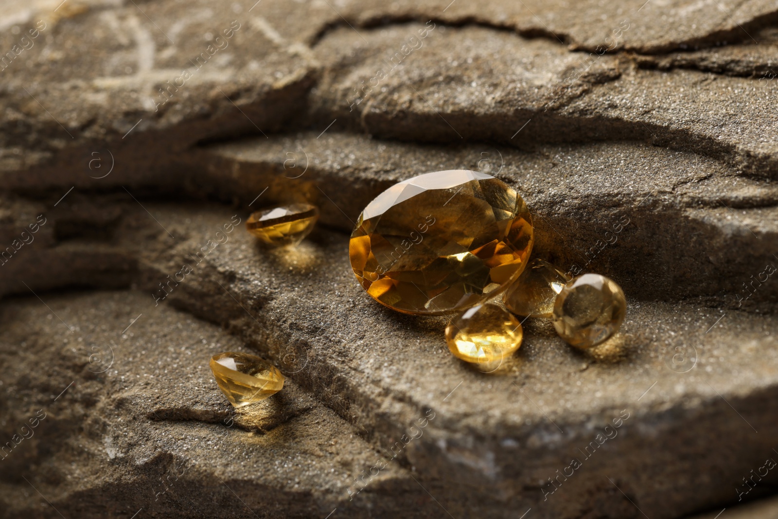 Photo of Beautiful yellow gemstones for jewelry on stone surface, closeup