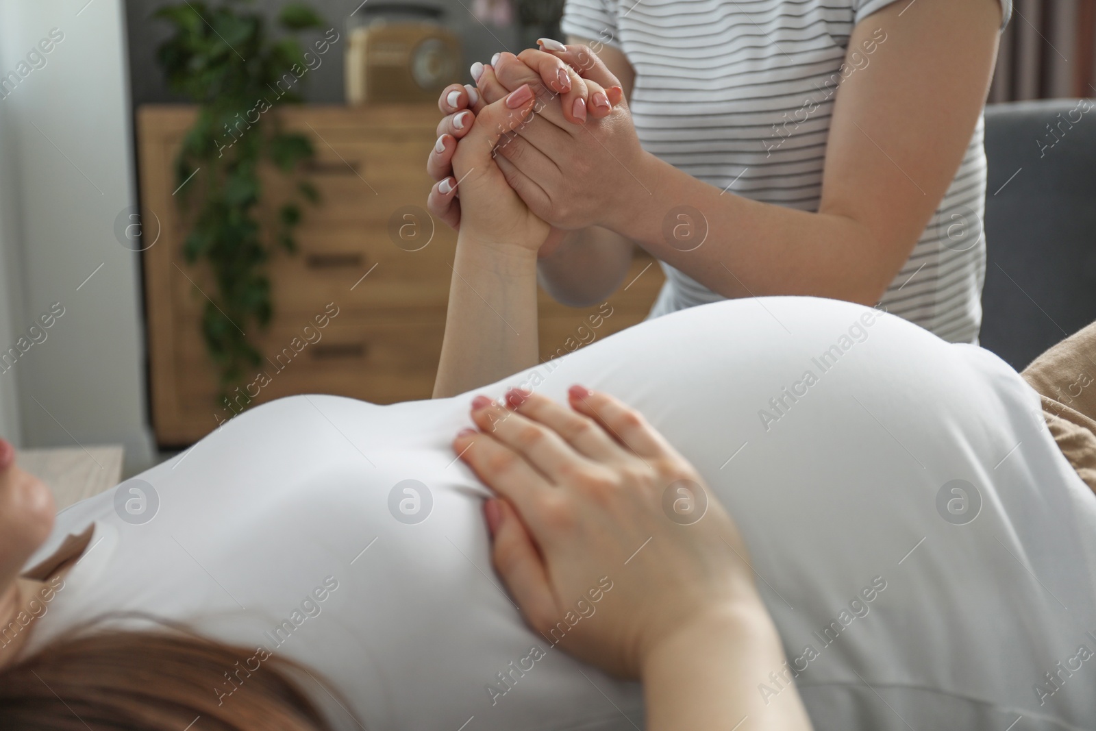 Photo of Doula taking care of pregnant woman indoors, closeup. Preparation for child birth