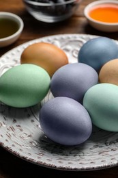 Photo of Easter eggs painted with natural organic dyes on wooden table, closeup