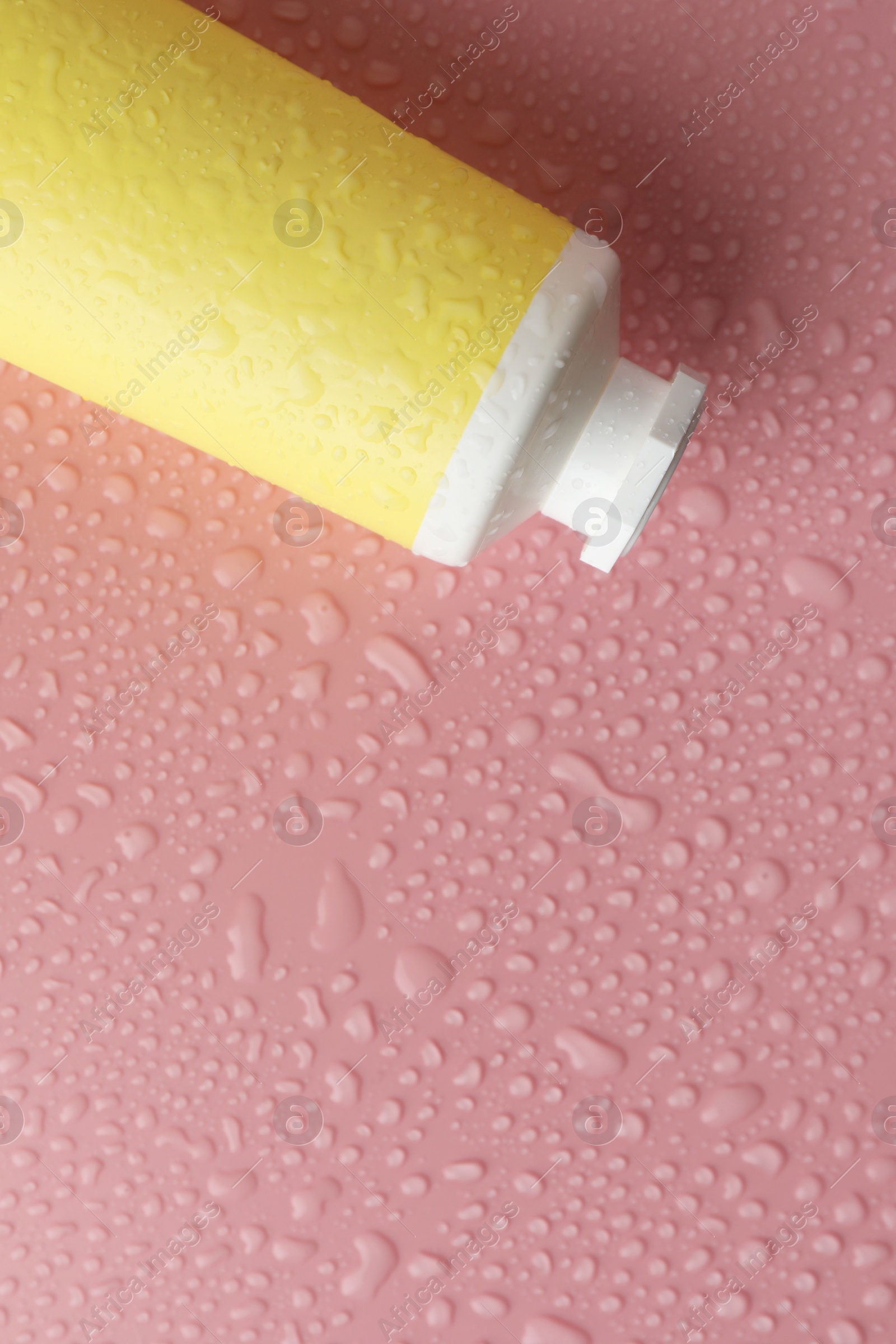 Photo of Moisturizing cream in tube on pink background with water drops, top view. Space for text