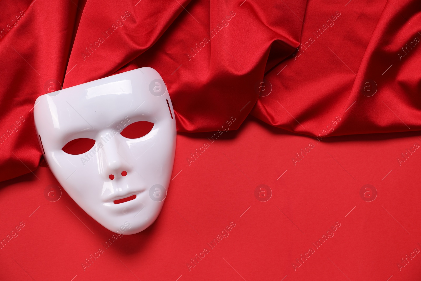 Photo of Theater arts. White mask and fabric on red background, top view. Space for text