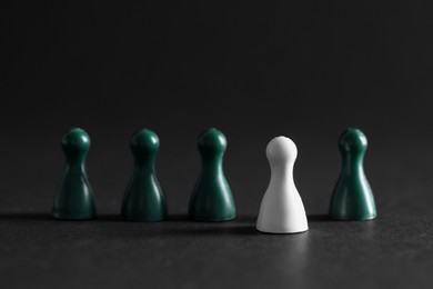 Photo of Choice concept. White pawn and green ones on dark table, closeup