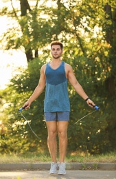 Photo of Young man training with jump rope in park