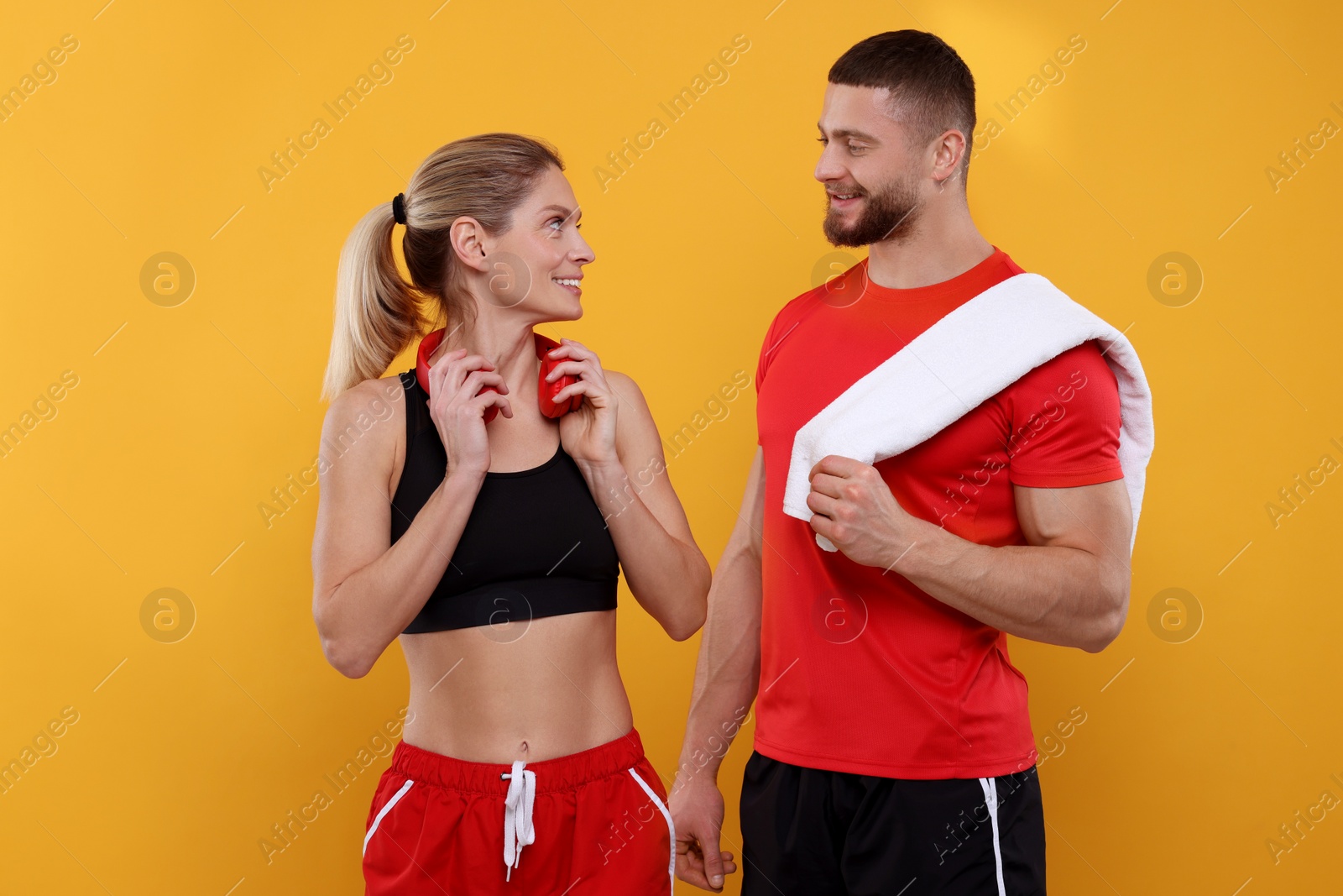 Photo of Athletic people with headphones and towel on yellow background