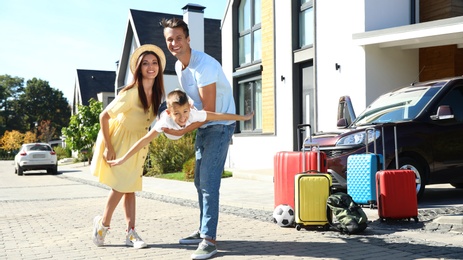 Photo of Happy family with suitcases near house outdoors. Moving day