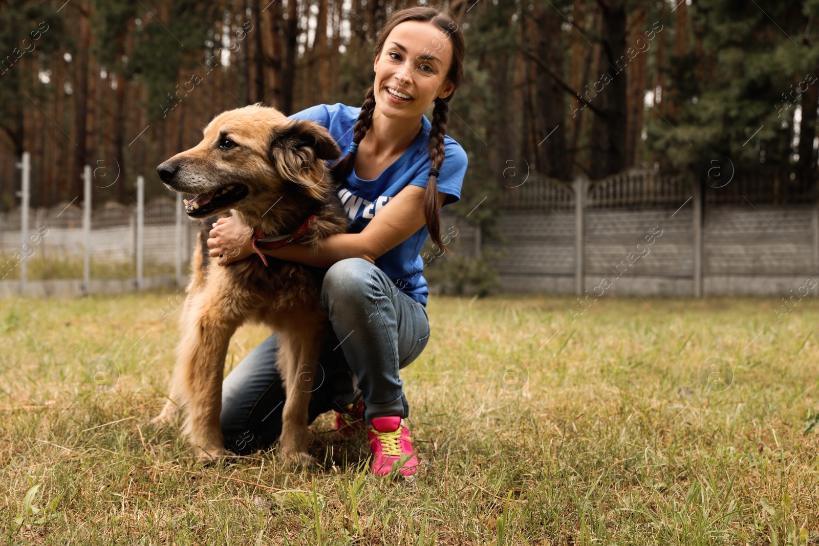 Photo of Female volunteer with homeless dog at animal shelter outdoors