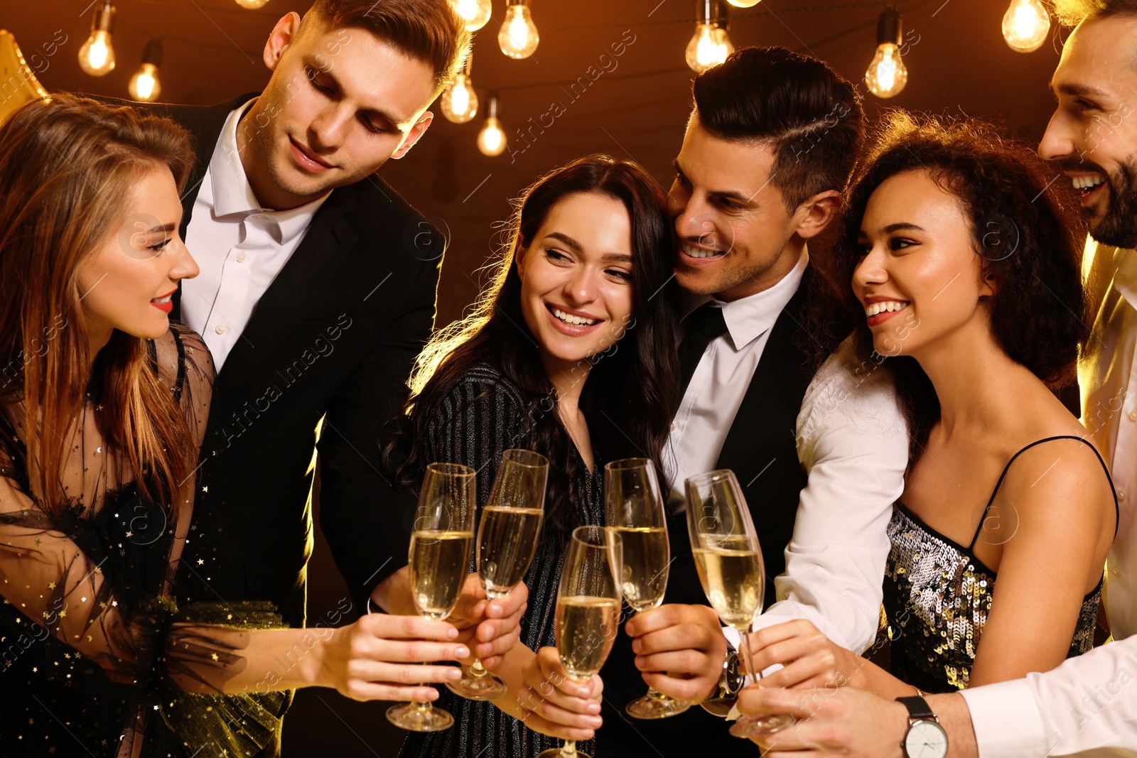 Photo of Happy friends with glasses of sparkling wine celebrating New Year indoors