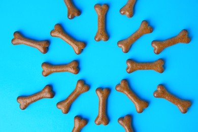 Bone shaped dog biscuits on light blue background, flat lay
