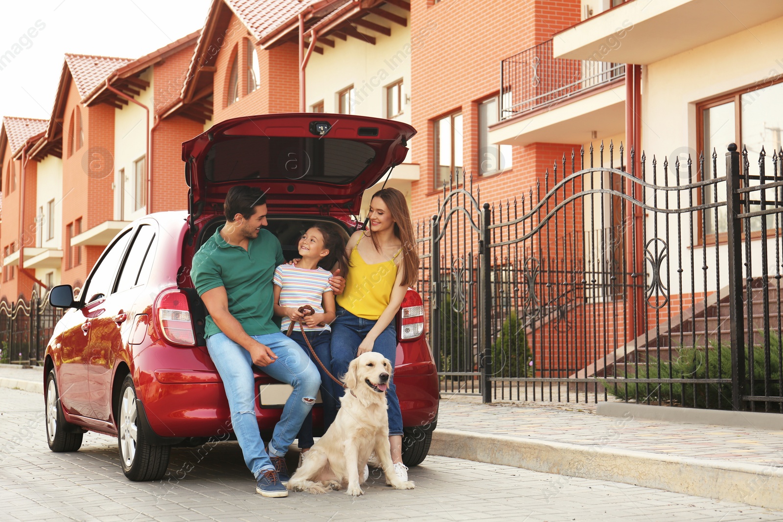 Photo of Happy family with dog near car on street