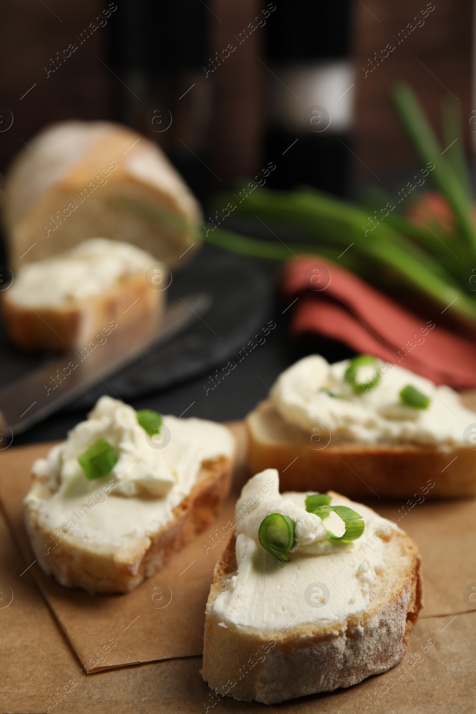 Photo of Bread with cream cheese and green onion on table, closeup