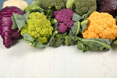 Photo of Different cabbages on wooden table. Healthy food