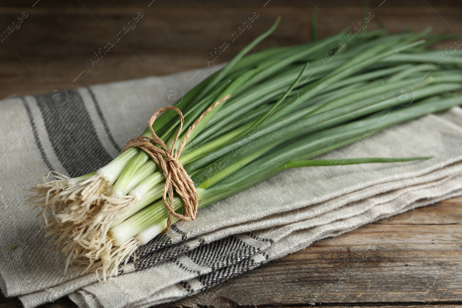 Photo of Fresh green spring onions on wooden table, closeup