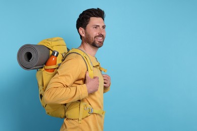Photo of Happy man with backpack on light blue background, space for text. Active tourism