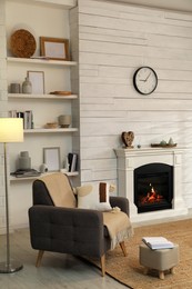 Photo of Stylish living room interior with comfortable armchair and decorative fireplace