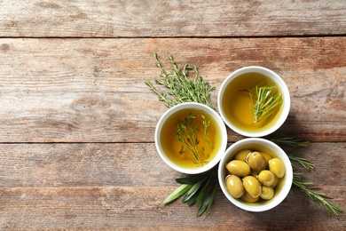 Photo of Beautiful composition with oil and ripe olives on wooden table, top view