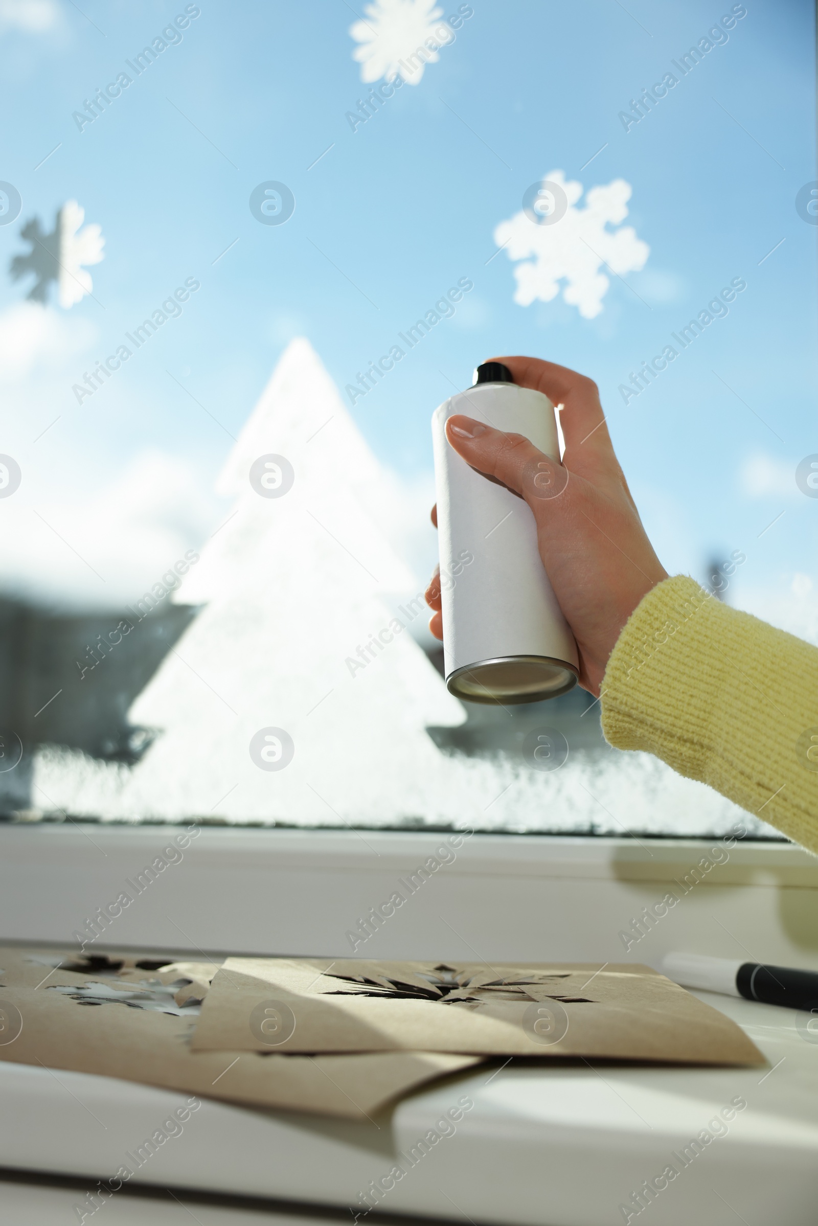 Photo of Woman using snow spray for decorating window at home, closeup