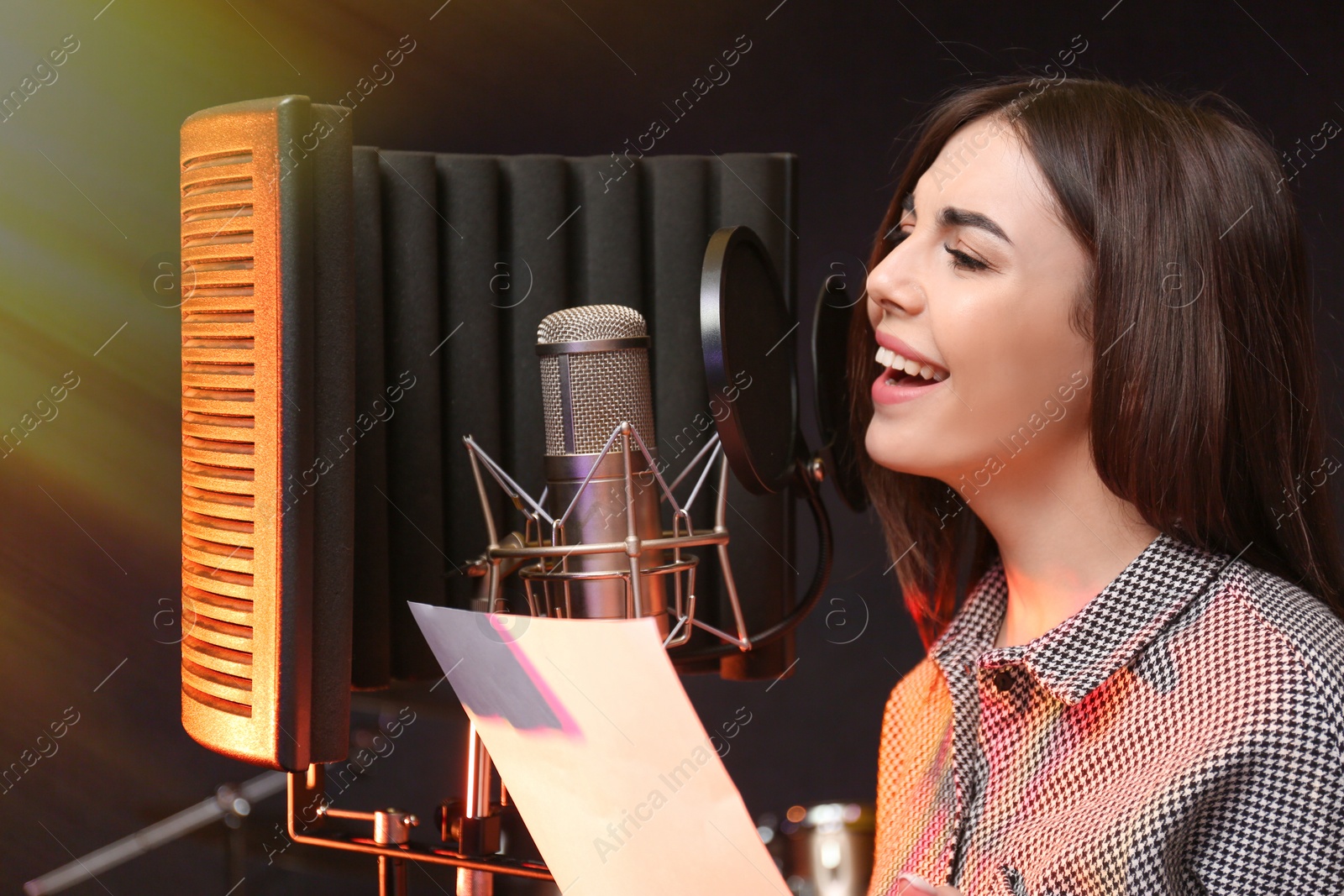 Photo of Young singer with microphone recording song in studio