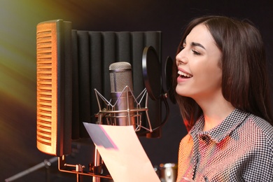 Photo of Young singer with microphone recording song in studio