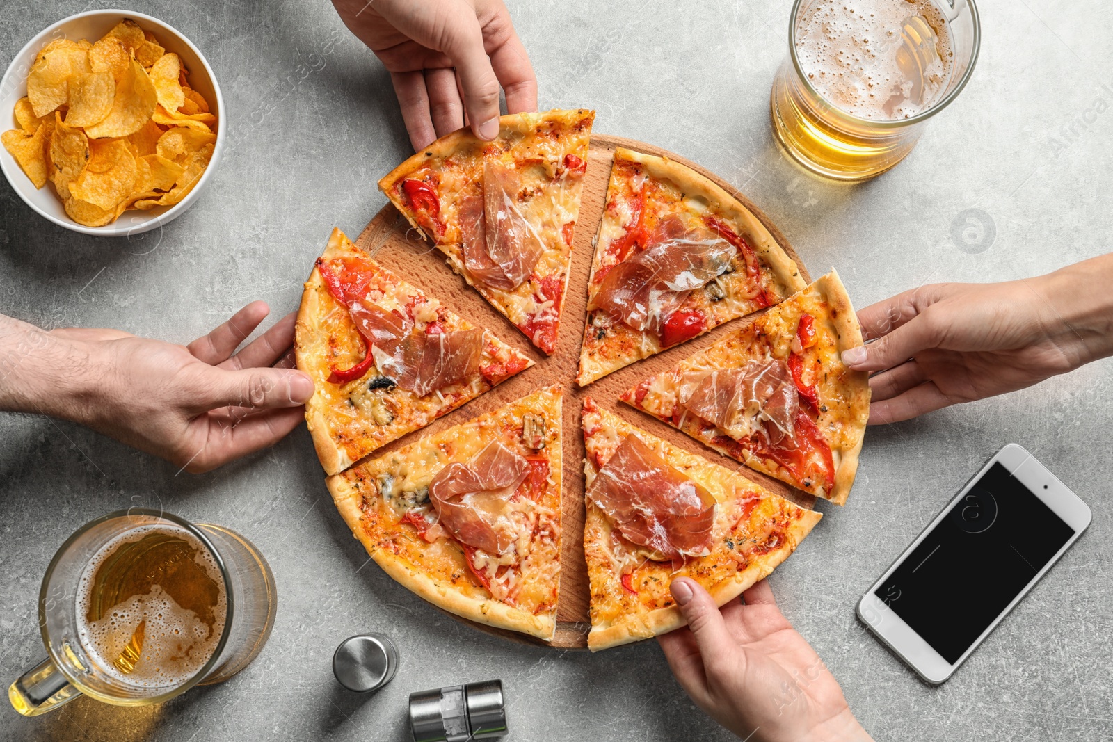 Photo of Young people taking slices of tasty pizza with meat at table, top view