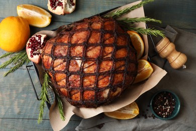 Delicious baked ham, orange slices, pomegranate and rosemary on rustic wooden table, flat lay