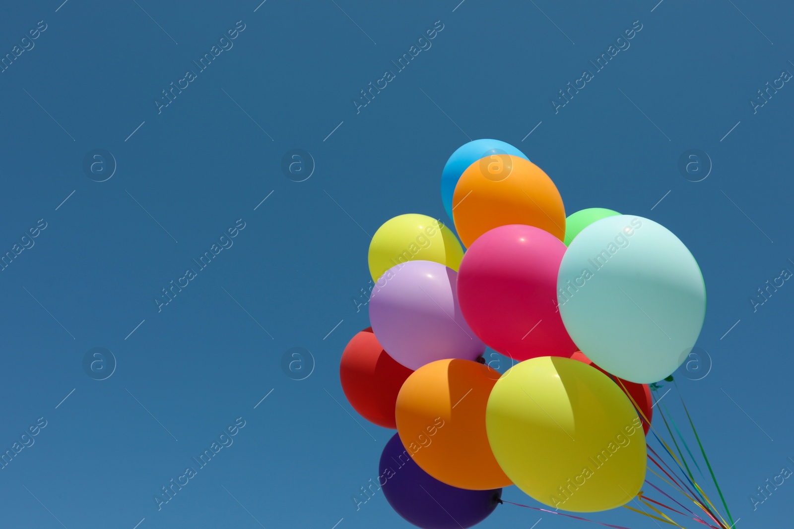 Photo of Bunch of colorful balloons against blue sky. Space for text