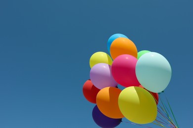 Photo of Bunch of colorful balloons against blue sky. Space for text