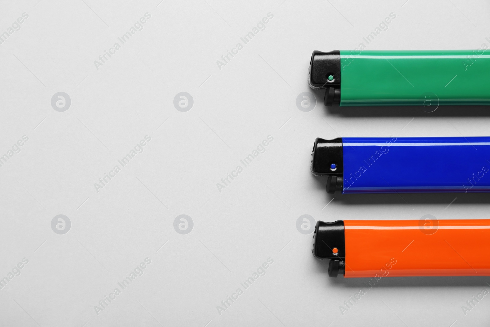 Photo of Stylish small pocket lighters on white background, flat lay. Space for text