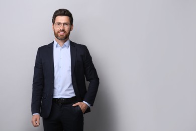 Portrait of handsome man in glasses on light grey background, space for text