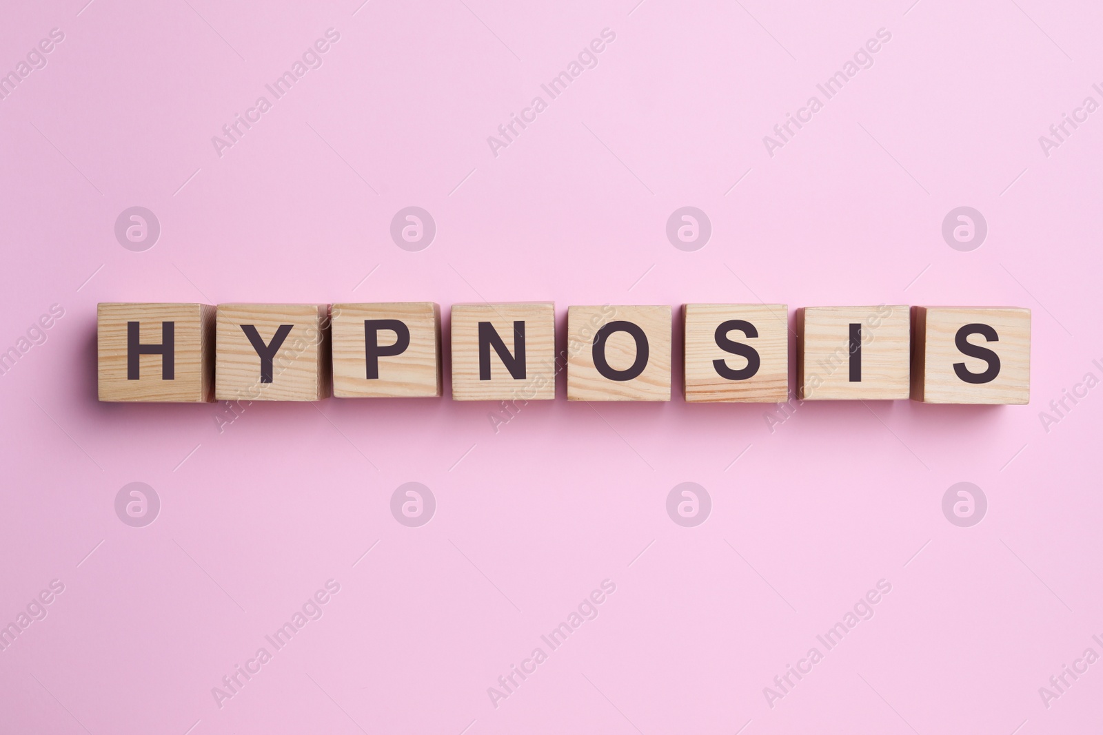 Photo of Wooden blocks with word HYPNOSIS on pink background, flat lay