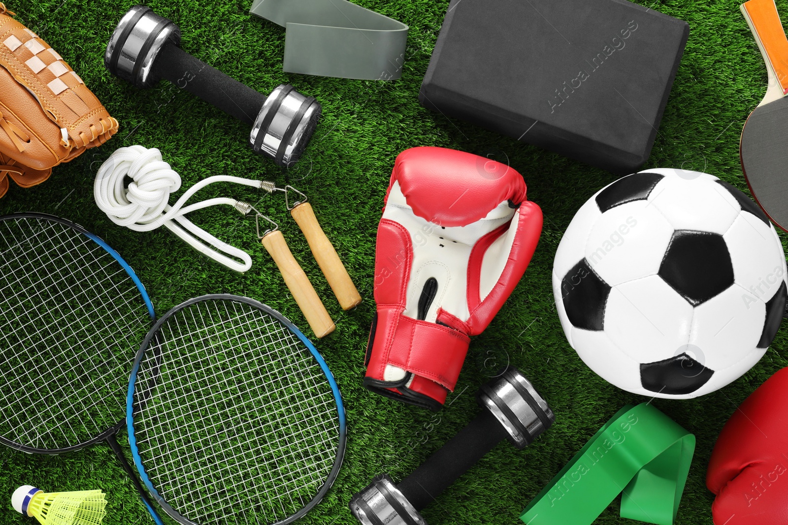 Photo of Different sport equipment on green grass, flat lay