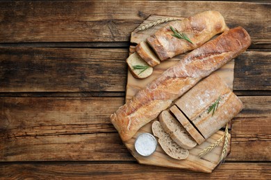 Photo of Cut fresh ciabatta and baguettes on wooden table, top view. Space for text