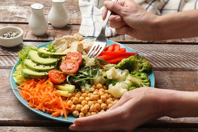 Photo of Balanced diet and healthy foods. Woman eating dinner at wooden table, closeup