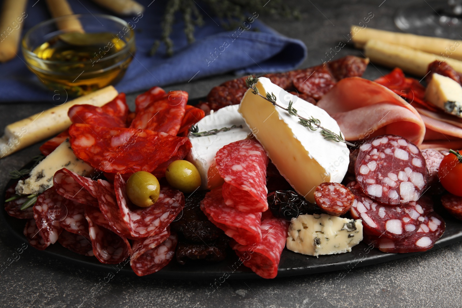 Photo of Tasty ham and other delicacies served on grey table, closeup