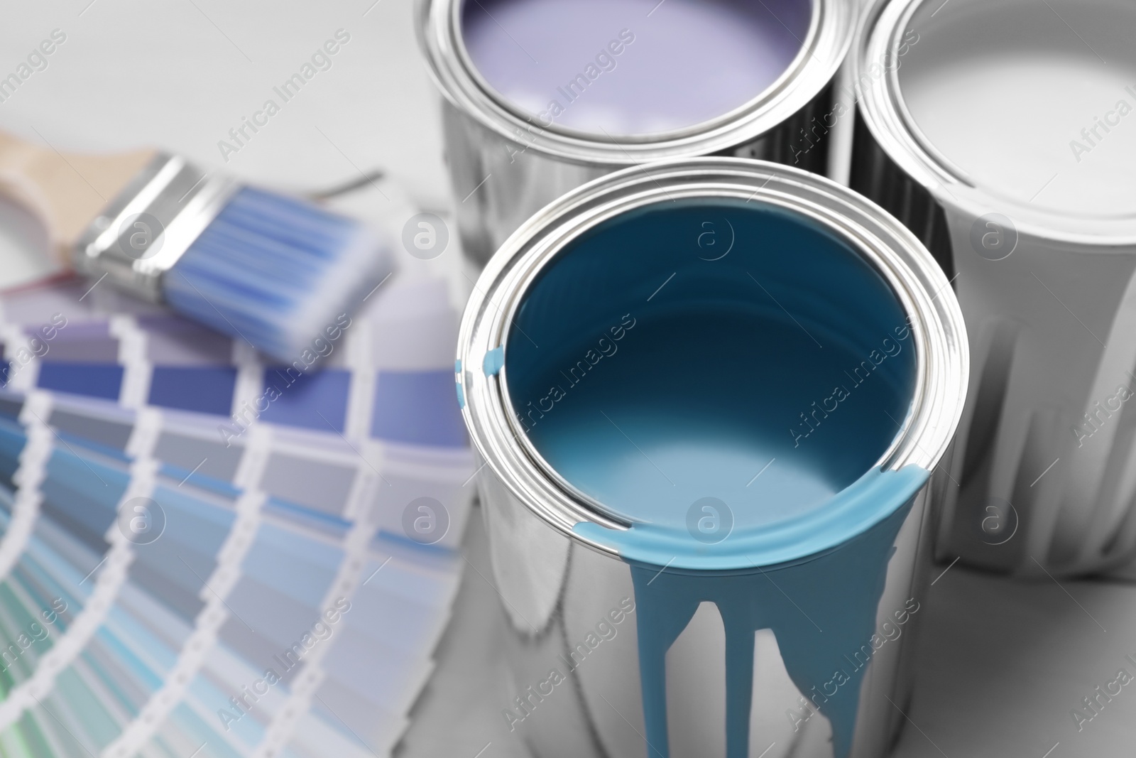 Photo of Cans of paints, brush and palette on white table