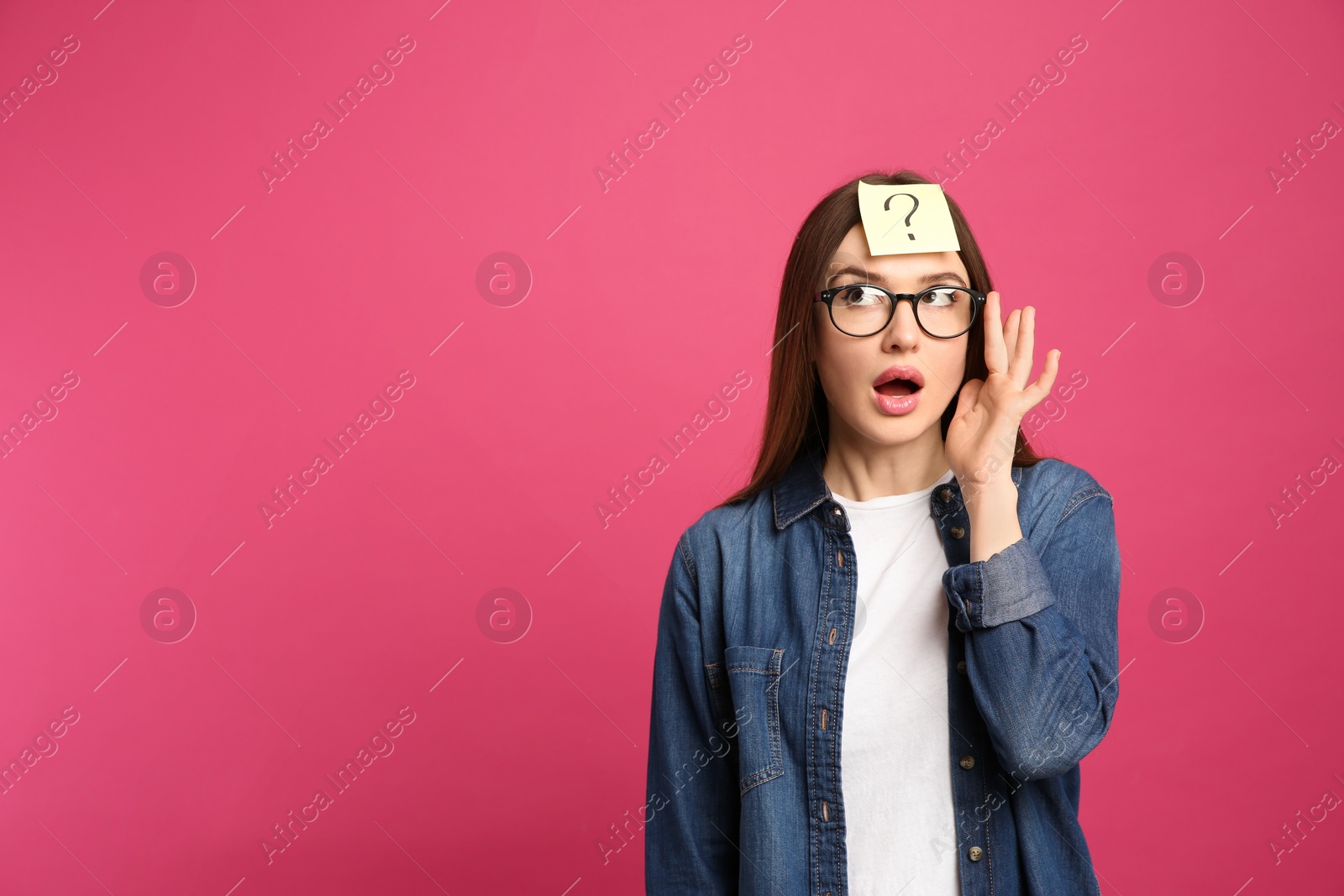 Photo of Emotional woman with question mark sticker on forehead against pink background. Space for text