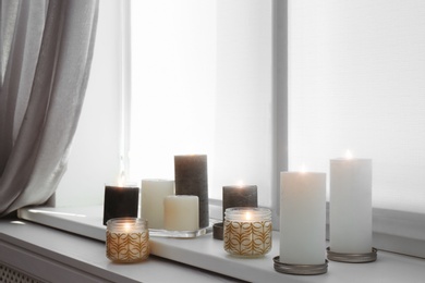 Photo of Burning candles on window sill in room