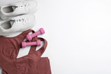 Photo of Sportswear and dumbbells on white background, flat lay with space for text. Gym workout