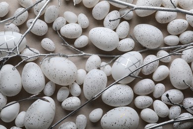 Photo of Many painted Easter eggs and tree twigs on grey background, flat lay