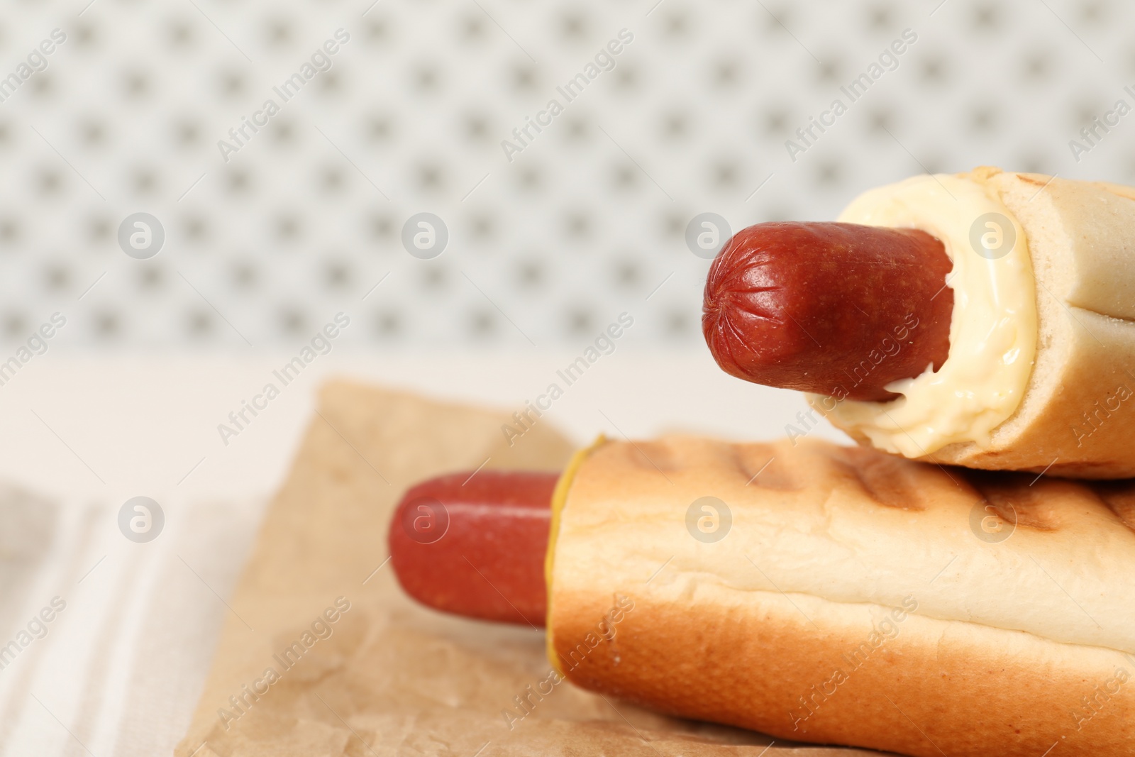 Photo of Tasty french hot dogs with different sauces on blurred background, closeup. Space for text